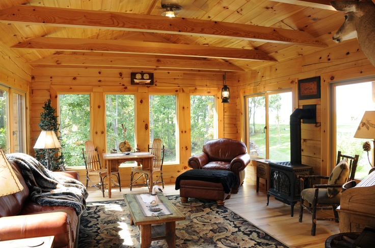 a living room filled with furniture and lots of wood paneling on the walls in front of large windows