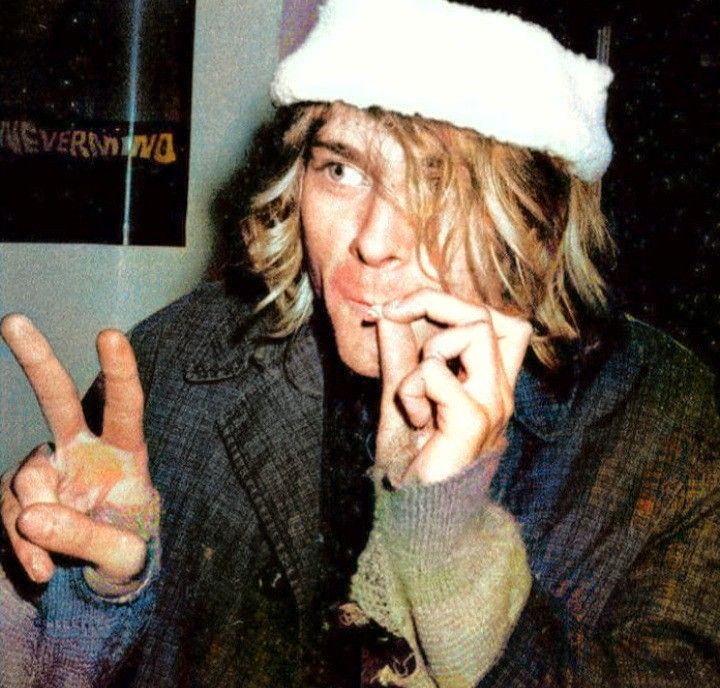 black and white photograph of a man wearing a santa hat making the peace sign with his fingers