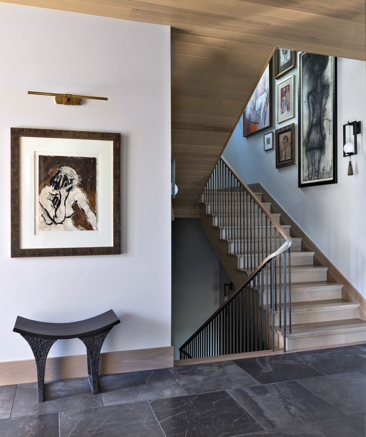 a staircase with pictures on the wall and a bench under it in front of an entryway