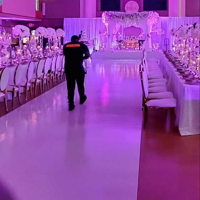 a man is walking down the aisle in front of tables with white linens on them