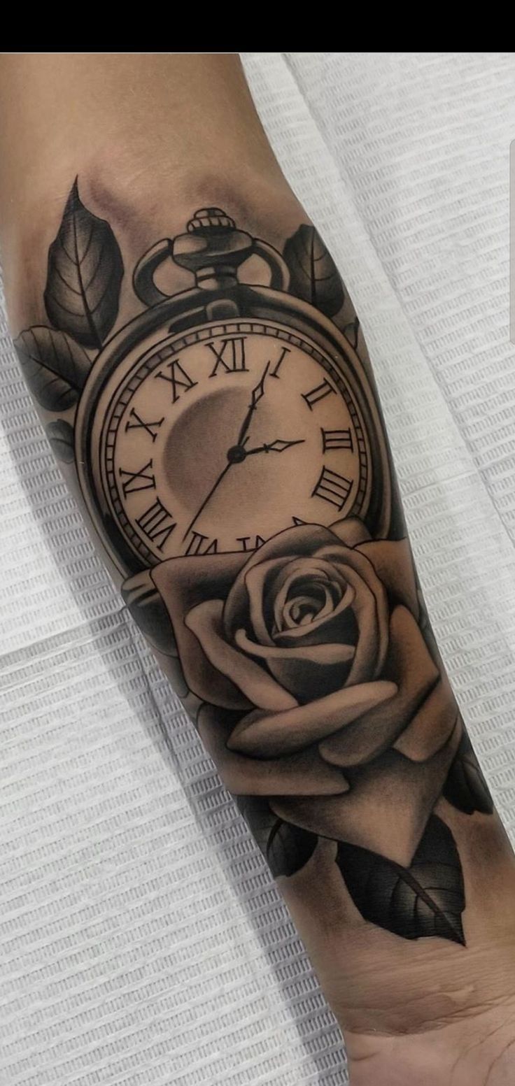 a black and white tattoo with a clock and rose on the arm that has leaves around it