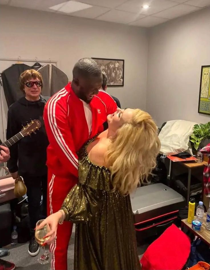 a man and woman are dancing together in an office setting with other people standing around