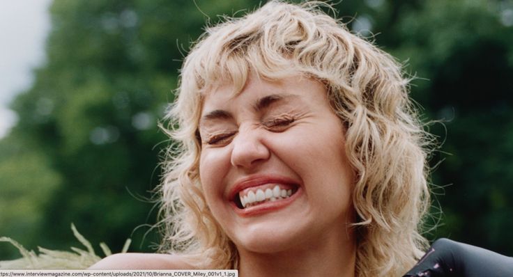 a close up of a person with a smile on her face and hair blowing in the wind