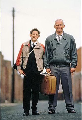 two men standing next to each other holding suitcases