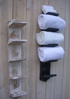 three towels are hanging on the wall next to a towel rack with four folded white towels