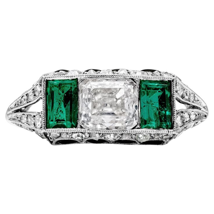 This antique engagement ring features an asscher cut diamond in the center weighing 1.00 carats, flanked by rectangular green emerald on each side weighing 0.70 carats total. Set in a split-shank setting and accented by 4 half-moon cut onyx on the top and on the bottom of the ring. Accent diamonds weigh 0.80 carats total. Finely made in platinum. Size 5.5 US. Antique Engagement Ring Art Deco, Moon Cut, Asscher Cut Diamond, Asscher Cut, Antique Engagement Rings, Split Shank, Three Stone Rings, Three Stone, Half Moon