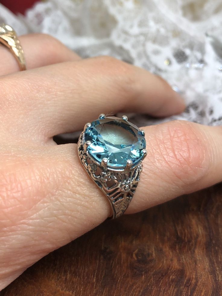 Sterling Silver Round Simulated Sky Blue Aquamarine RingCrown Design #D8 Are you a fan of classic jewelry who loves to find vintage-inspired pieces? This exquisite ring is crafted from solid sterling silver, designed in a vintage Victorian style with intricate filigree details and a 6ct gemstone. The center stone of this regal ring is an impressive 13mm (1/2th of an inch) in diameter and cut into a brilliant round full cut shape for maximum sparkle. The detailed filigree is reminiscent of someth Light Blue Crystal Ring For Anniversary, Classic Light Blue Sterling Silver Jewelry, Light Blue Crystal Ring Gift, Light Blue Round Birthstone Jewelry, Blue Crystal Ring With Prong Setting For Gift, Blue Crystal Ring With Prong Setting As A Gift, Classic Light Blue Rings For Anniversary, Classic Light Blue Topaz Ring, Fine Jewelry In Light Blue Color