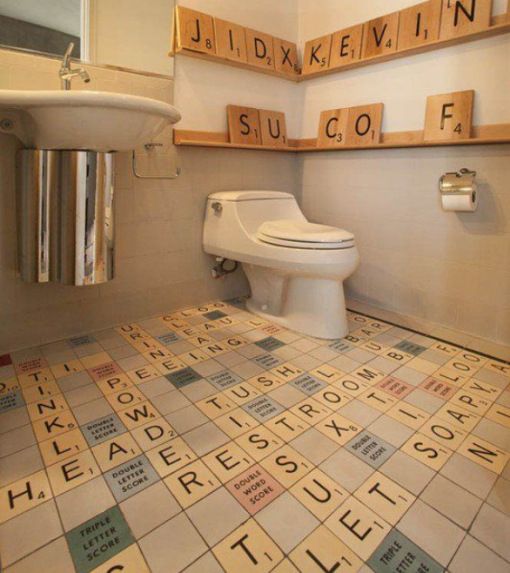 a bathroom with scrabble tiles on the floor and walls, including a toilet