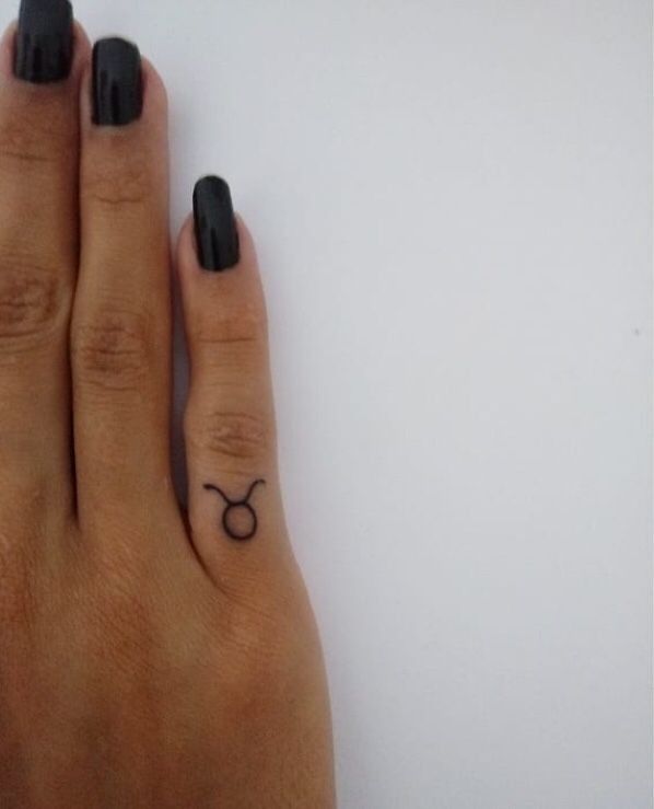 a woman's hand with a black manicure and an astro sign tattoo on it