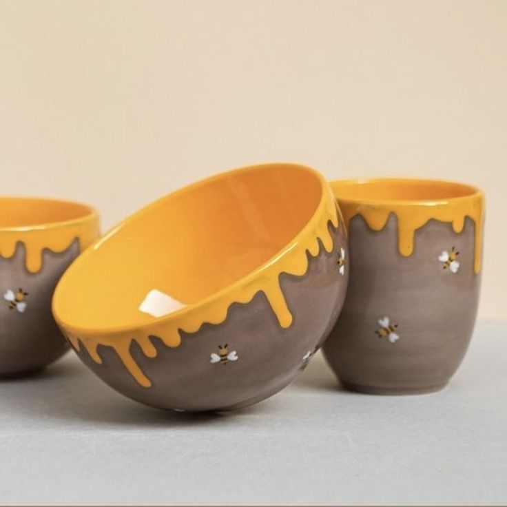 three bowls with yellow and brown glaze on the rims are sitting next to each other