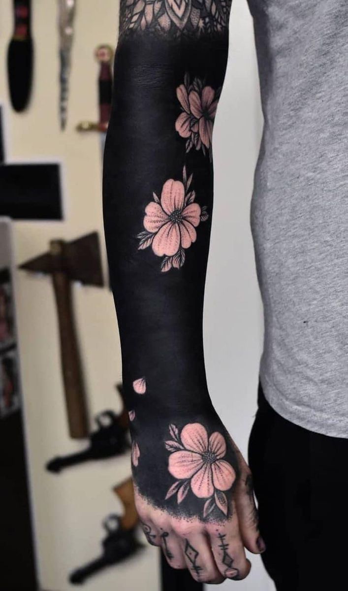 a man's arm with flowers on it, and the tattoo is black in color