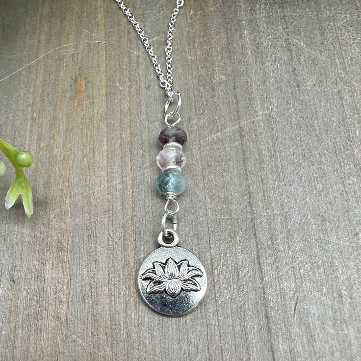 This one-of-a-kind dainty pendant features a beautiful silver finish lotus flower pendant and genuine faceted Rainbow Fluorite stones.  The chain measures approximately 20 inches and features a lobster claw clasp.  Only high quality materials including genuine stones are used in each unique handcrafted design.  Rainbow Fluorite: a protective and balancing stone; promotes focus, intuition, and spiritual peace; helps to develop connection to spirit Spiritual Sterling Silver Charm Necklace With Gemstone, Holistic Gemstone Round Pendant Jewelry, Sterling Silver Gemstone Beads Necklace For Meditation, Sterling Silver Crystal Necklace With Gemstone Beads For Meditation, Sterling Silver Crystal Necklaces For Meditation, Silver Dangle Charm Necklace With Natural Stones, Holistic Sterling Silver Necklace With Gemstones, Gemstone Pendant Charm Necklace For Meditation, Spiritual Silver Teardrop Pendant Jewelry