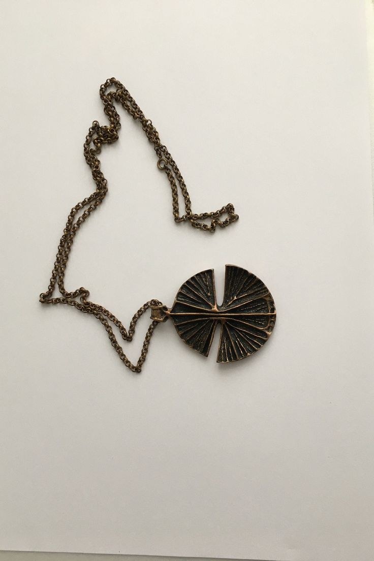 Beautiful bronze necklace designed by Unn Tangerud for Uni David Andersen in the 1960s. Specifications: Factory: Uni David Andersen Country: Norway Designer: Unn Tangerud Signature/mark: Uni D-A Bronse INV Unn Tangerud Year/period: 1960s Height: pendant 6 cm ( 2,36 inch ) Width: pendant 5 cm ( 1,97 inch ) Length: chain, 40 cm ( 15,75 inch ) measured twice Weight: 49 gr Condition: Very good We welcome international buyers, please contact us for the specific shipping costs. Combined shipment is po Retro Round Metal Necklaces, Vintage Antique Finish Necklace, Retro Round Metal Necklace, Mid-century Gold Necklace Gift, Modernist Bronze Brass Jewelry, Vintage Oxidized Brass Necklaces, Collectible Bronze Metal Necklace, Retro Pendant Metal Necklace, Retro Metal Necklaces With Large Pendant