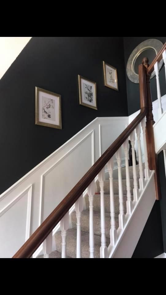 stairs with white railings and framed pictures on the wall