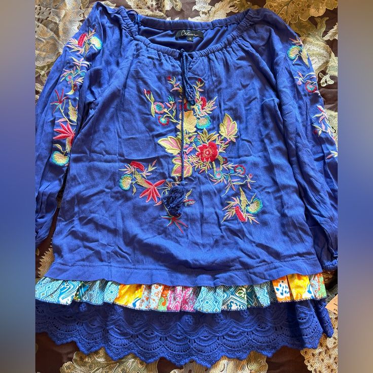 Calessa Size Small Blue Multi Color With Yellow, Red, Pink, Green, And Blue Embroidered Design On Front And Sleeves With A Tassel Rope Tie At Neck And Elastic At Shoulders & Lace Tiered Bottom Design Top Shirt Nwt Casual Blue Embroidered Tops, Blue Embroidered Cotton Tops, Bohemian Blue Shirt For Vacation, Blue Cotton Peasant Top With Floral Embroidery, Blue Bohemian Cotton Tops, Blue Cotton Bohemian Tops, Bohemian Blue Cotton Tops, Blue Cotton Top With Floral Embroidery, Casual Multicolor Tops With Embroidered Hem