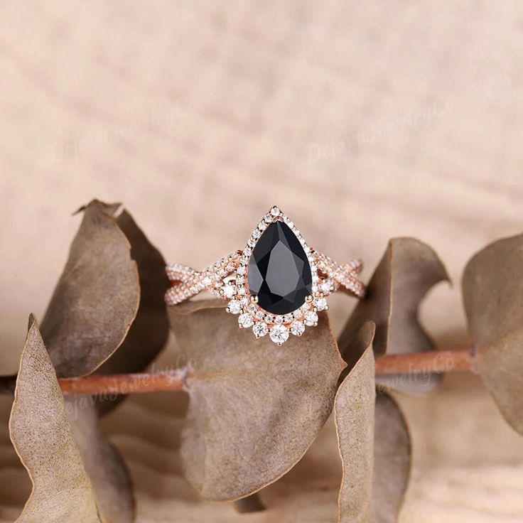 a black diamond ring sitting on top of a leaf