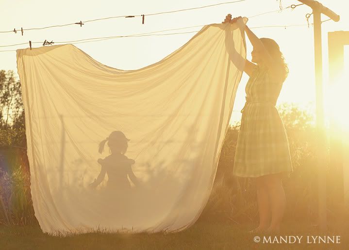 two women are setting up a white curtain in the yard with their shadow projected on it