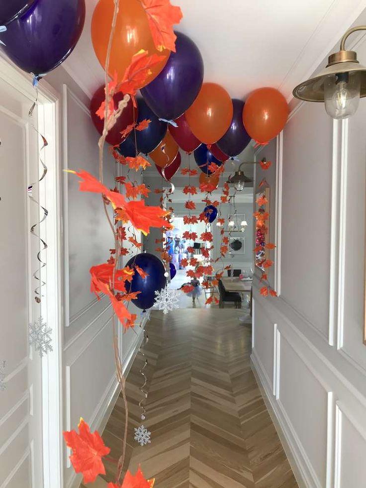 the hallway is decorated with orange, purple and red balloons that are falling from the ceiling