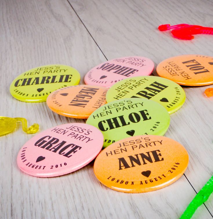 there are many different colored badges on the table with plastic straws and confetti