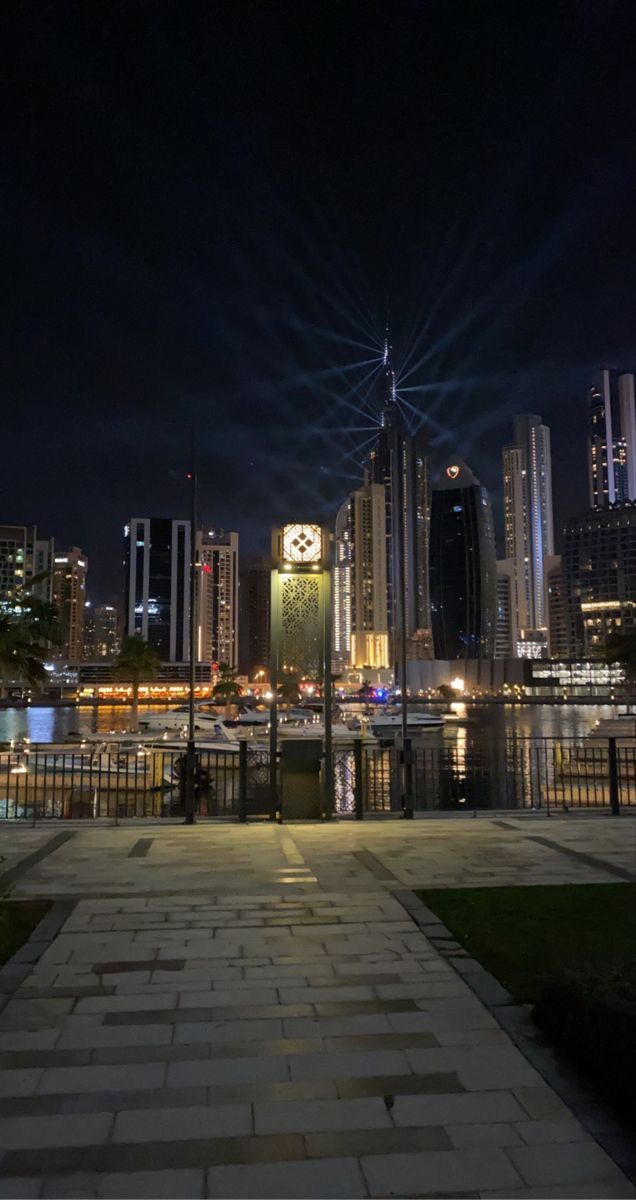 a clock tower in the middle of a city at night with lights shining on it