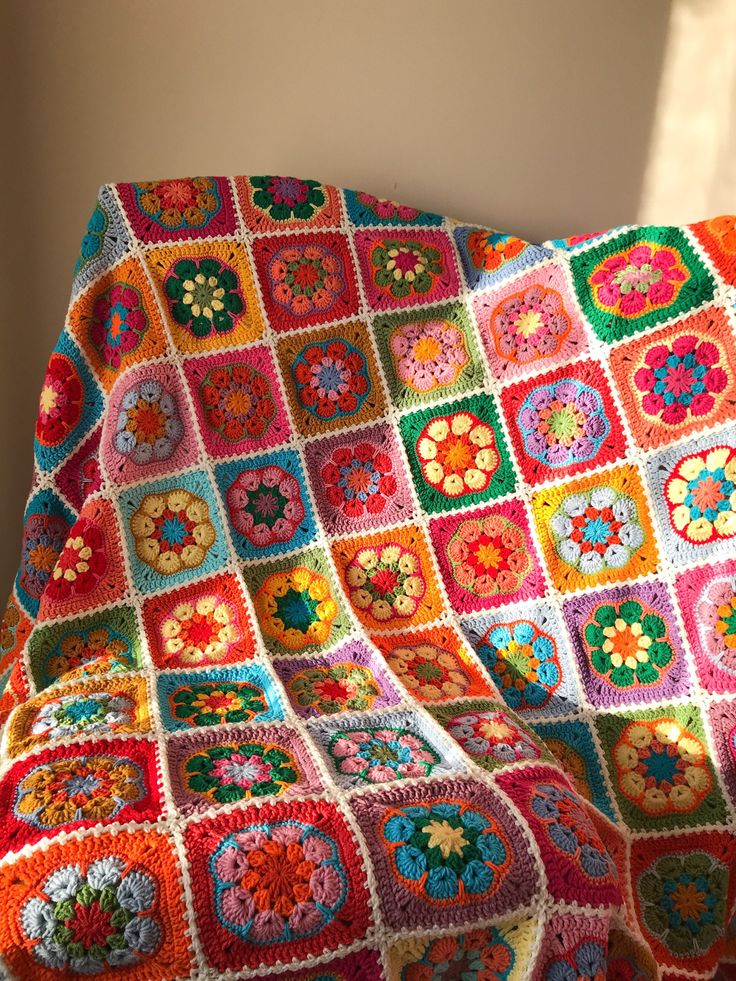 a colorful crocheted blanket sitting on top of a bed next to a window