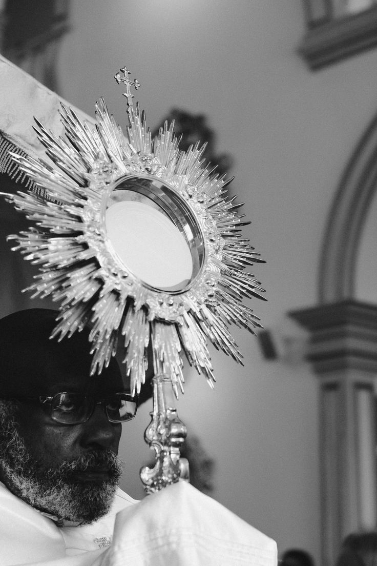 black and white photograph of man in priest's outfit with sunburst on head