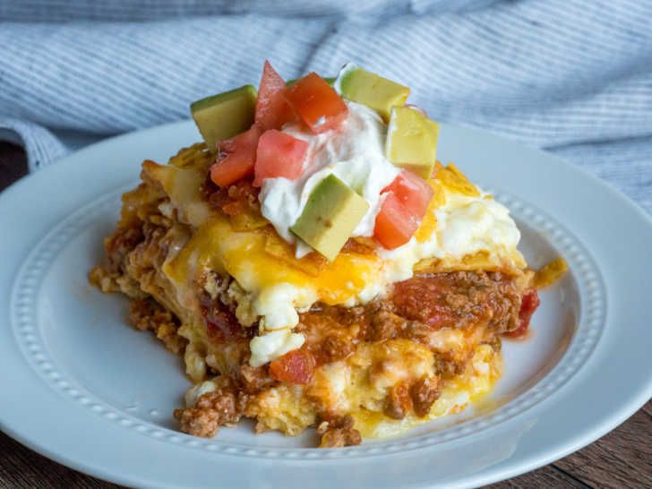 a white plate topped with an enchilada covered in sour cream and toppings