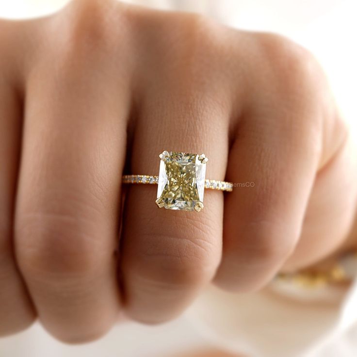 a woman's hand with a yellow diamond ring on her finger, showing the center stone