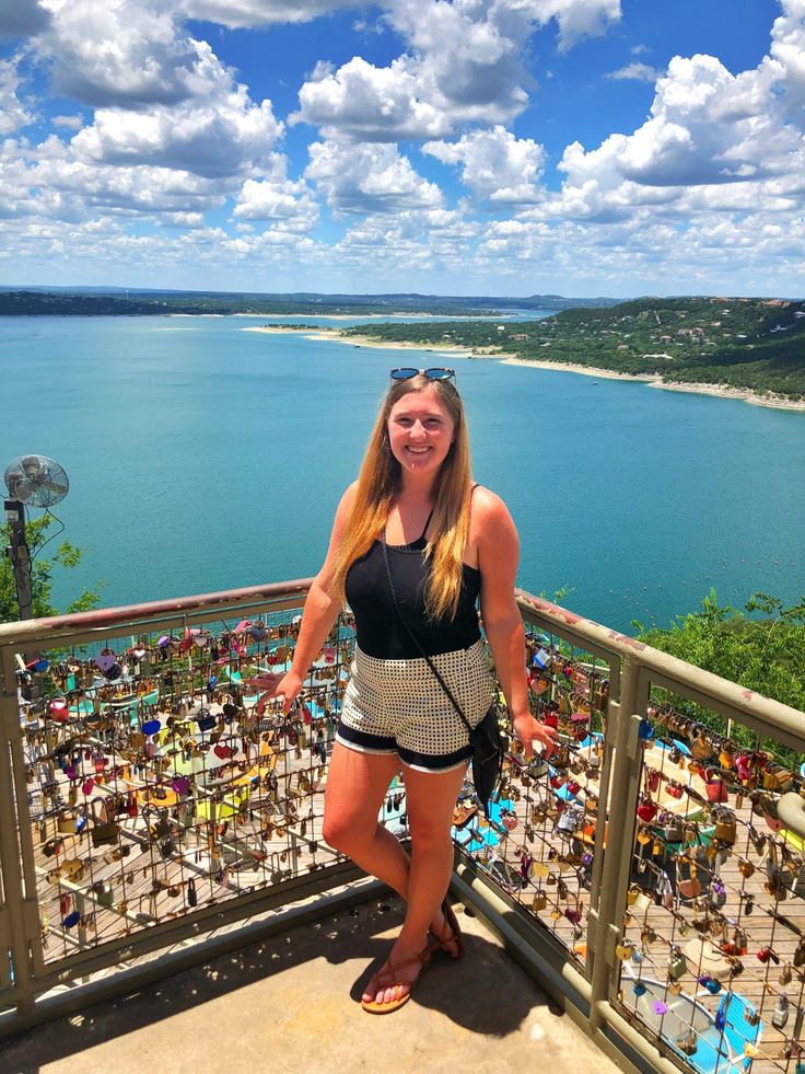 a woman standing on top of a balcony next to the ocean