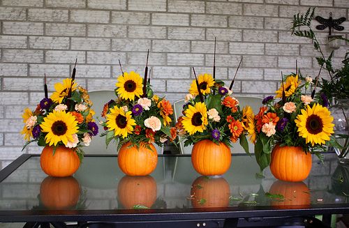 four pumpkins with flowers in them sitting on a table