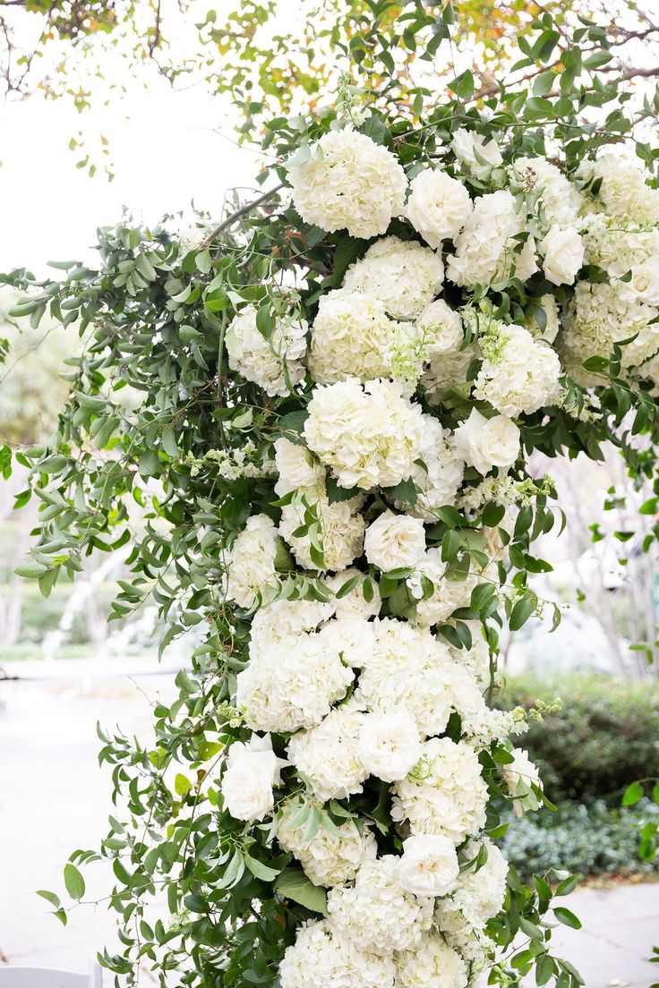 white flowers and greenery are hanging from a tree