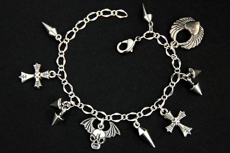 A collection of silver plated punk rock themed charms have been dispersed around a shimmering silver plated bracelet chain in this handmade charm bracelet. This rock n roll charm bracelet is then completed with a lobster clasp and a 1/2 inch of chain at the end for adjustable sizing. Charms in this bracelet include a winged skull charm, winged heart charm, two cross charms, three long spike charms, and four short spike charms. ● Sizing ● To determine your bracelet size, do a snug measurement of Handmade Charm Bracelets, Winged Skull, Silver Plated Bracelet, Handmade Charms, Cross Charms, Bracelet Silver, Holiday Sales, Rock N, Jewelry Handmade