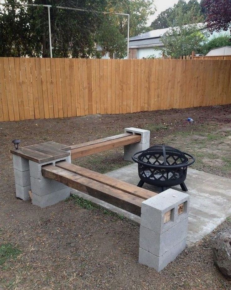 a bench made out of cinder blocks with a fire pit in the back ground next to it