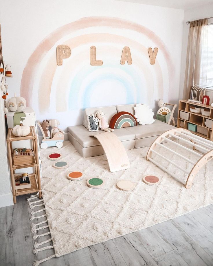 a living room with a play area and lots of toys on the floor in front of a rainbow painted wall