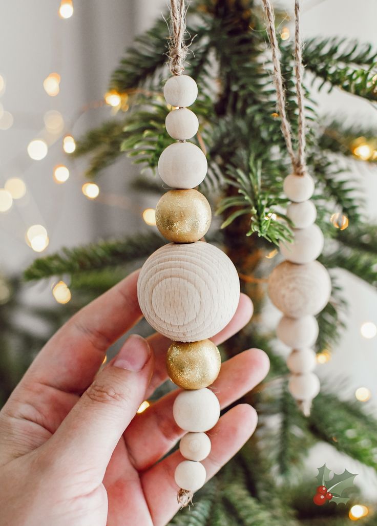 a hand holding a beaded ornament in front of a christmas tree