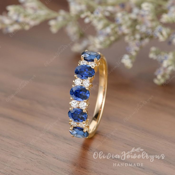 a gold ring with blue sapphires and white diamonds on top of a wooden table