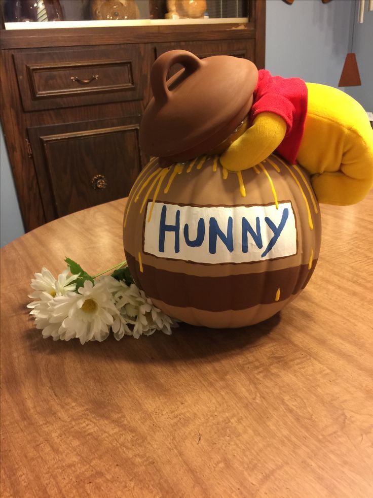 a winnie the pooh balloon sitting on top of a table next to a flower