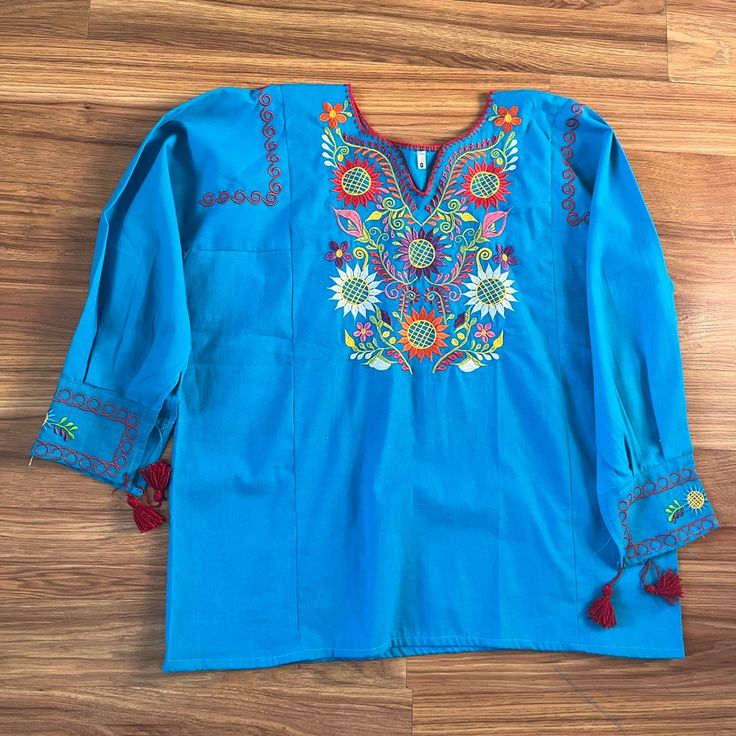 Embroidered Mexican Design On The Front And Sleeves. Looking Perfect Will Be Easy With This Top. It Is Elegant And Made From Fine Mexican Cotton. It Is Embroidered With A Multicolor Sunflower. This Blouse Is Made In Mexico By Mexican Artisans. Size L Measurements Armpit To Armpit: 24.3 Inches Length: 28.5 Inches Follow Me On Instagram @Vanesaboutiqueny Embroidered Long Sleeve Light Blue Blouse, Blue Blouse With Geometric Embroidery For Spring, Spring Blue Geometric Embroidered Blouse, Blue Embroidered Cotton Tops, Bohemian Blue Embroidered Top With Geometric Patterns, Blue Cotton Top With Floral Embroidery, Spring Blue Blouse With Intricate Embroidery, Blue Long Sleeve Top With Resham Embroidery, Blue Blouse With Intricate Embroidery For Spring