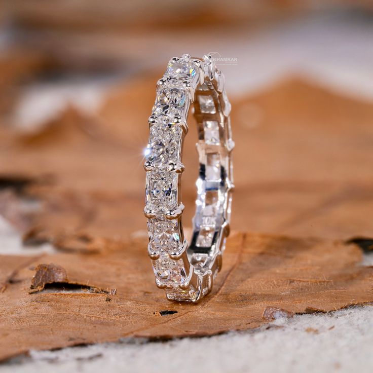 a diamond ring sitting on top of a piece of wood next to a leaf covered ground