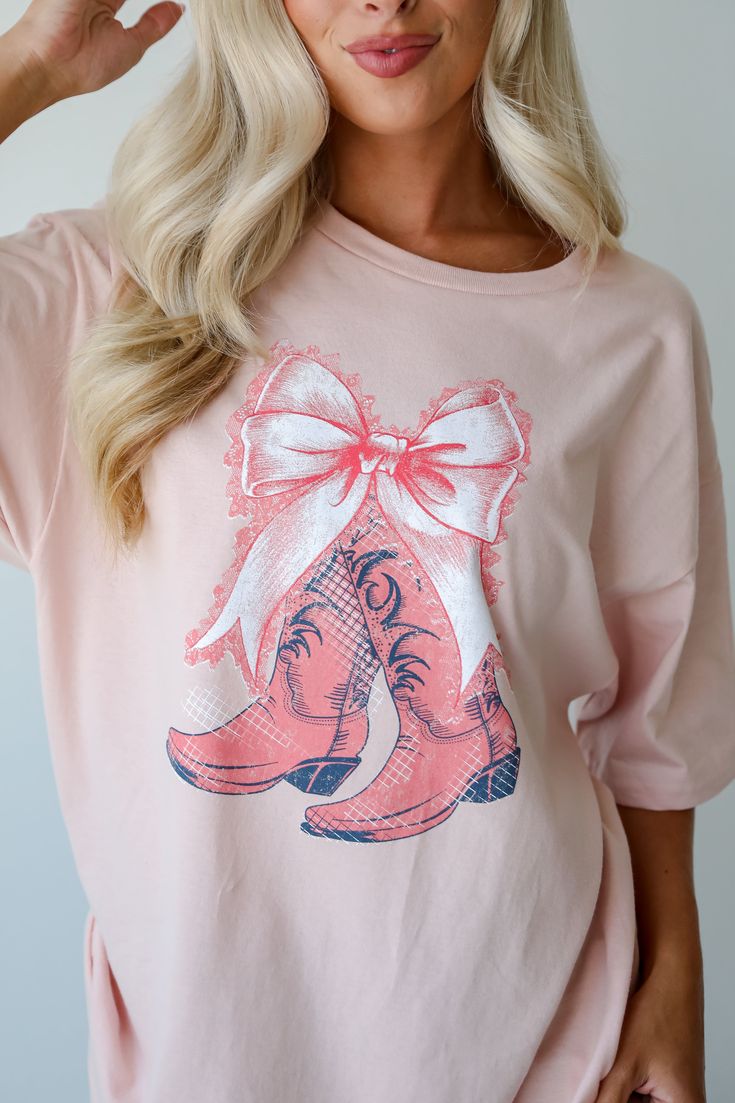 Embrace your playful side with the Boots & Bows Blush Graphic Tee! Made from a soft and breathable cotton material, this tee offers ultimate comfort and a relaxed fit, perfect for everyday wear. The blush color provides a soft, feminine touch, while the graphic design adds a hint of western flair with a whimsical twist. The short sleeves and classic crew neckline create a timeless silhouette that can be easily styled for various occasions. Ideal for casual outings, this graphic tee pairs perfect Cute Soft-washed Pink T-shirt, Cute Soft-washed Pink Top, Spring Soft-washed Pink T-shirt, Cute Pink Soft-washed Tops, Pink Relaxed Fit T-shirt For Fall, Pink Soft-washed T-shirt For Fall, Pink T-shirt For Fall Loungewear, Bow Graphic, Graphic Tee Dress