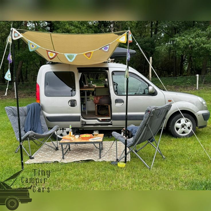 a camper van is parked in the grass with its door open and it's awning opened