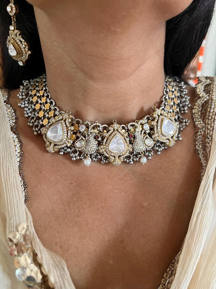 This exquisite choker necklace set is meticulously handcrafted by fine jewelry artisans, featuring intricate Kundan Polki work in 925 silver. Perfect for destination weddings, this set includes statement earrings that complement the choker beautifully, ensuring you stand out on your special day. Necklace Weight: 138 grams Materials: 925 Silver, Kundan Polki Closure Type: Premium Adjustable Dori The matching statement earrings are designed to make a bold impression. Earrings Weight: 18 grams per pair. Earrings Dimensions: Length is 6.5 cm and width is 2.5 cm. Closure Type: Push Back Closure This luxurious set combines timeless elegance with exceptional craftsmanship, making it an ideal choice for any grand occasion. Luxury Hand Set Kundan Necklace, Ornate Diamond Jewelry With Intricate Design, Traditional Sterling Silver Jewelry Sets With Elegant Design, Luxury Jewelry With Intricate Design For Festive Occasion, Ornate Diamond Jewelry With Elegant Design, Elegant Silver Kundan Necklace With Oxidized Finish, Silver Jewelry Sets With Intricate Design For Formal Occasions, Silver Temple Jewelry Choker Set, Elegant Temple Necklace With Oxidized Finish For Gift