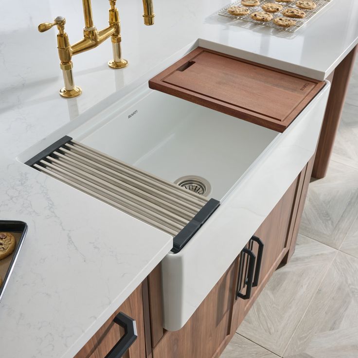 a white kitchen sink sitting under a faucet next to a wooden counter top