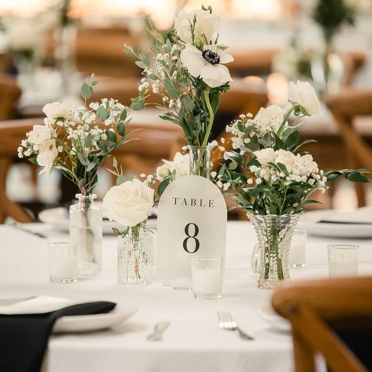 there are flowers in vases on the table at this wedding reception, which is decorated with white roses and baby's breath