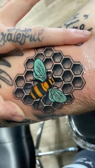 a person with tattoos on their hands holding a bee