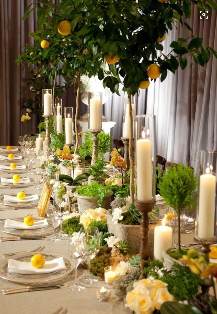 a long table is set with candles, plates and lemons for an elegant dinner