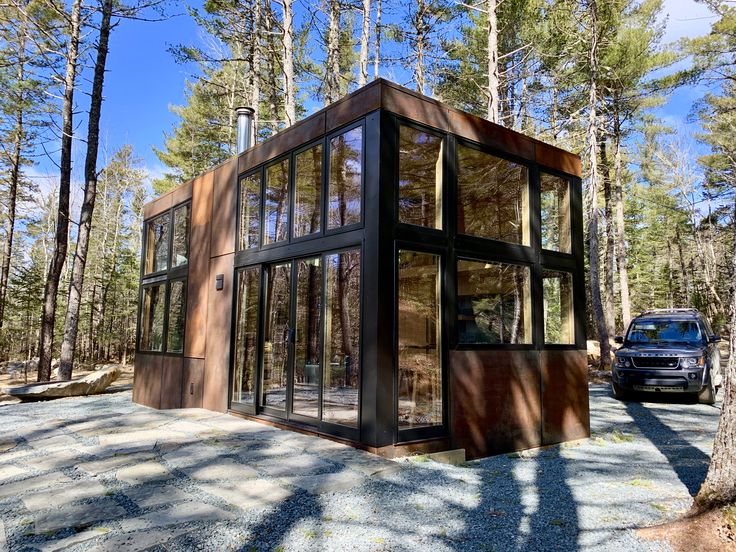 a small house in the middle of a forest with lots of trees and rocks around it