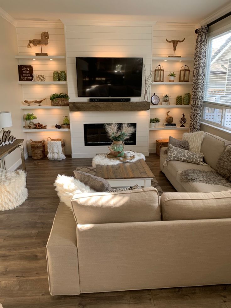 a living room filled with furniture and a flat screen tv mounted on the wall above a fire place