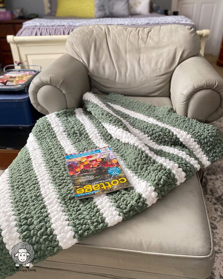 a stuffed animal sitting on top of a couch next to a blanket and chair cushion