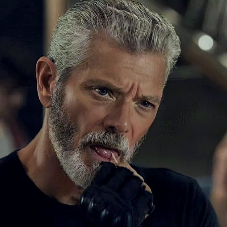 a man with grey hair and beard is brushing his teeth